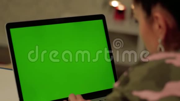 穿迷彩服的女孩在带绿色屏幕的笔记本电脑上工作视频的预览图