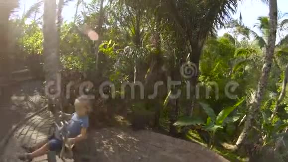 一个小男孩在热带丛林中荡秋千时的慢动作镜头童年概念儿童旅行视频的预览图