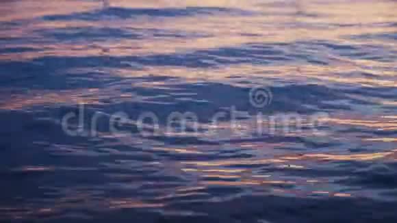 在紫色粉色夕阳的背景下海面上平静的波涛视频的预览图