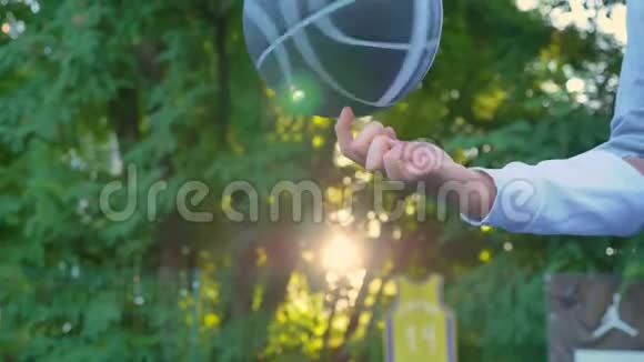 篮球在一根手指上旋转日落时停在公园里背景是树木开放区域视频的预览图