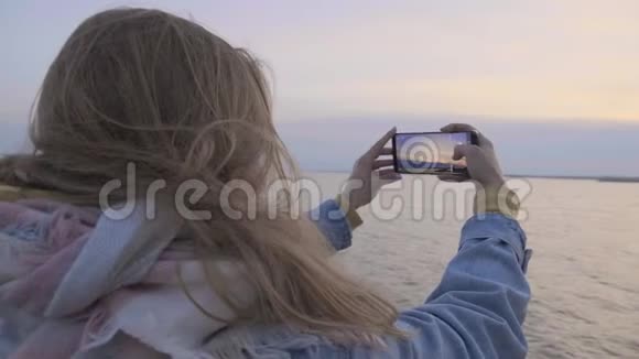 年轻女子打电话拍日落海边照片视频的预览图