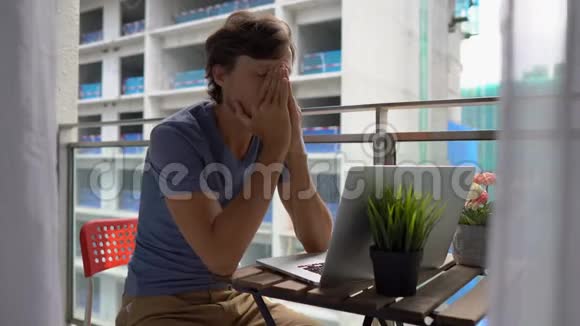 年轻人坐在阳台上拿着笔记本在附近的一个建筑工地上大声喧哗视频的预览图