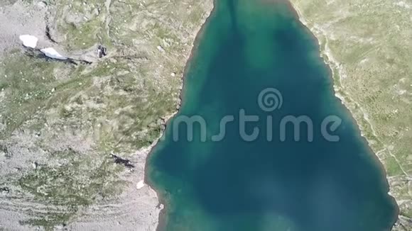 上上下下无人驾驶飞机鸟瞰Barbellino湖一个自然的高山湖在夏天雪在融化视频的预览图