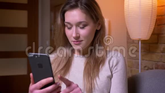 用手机拍摄年轻迷人的白种人黑发女性的特写肖像并在镜头中显示绿色彩色屏幕视频的预览图