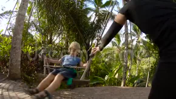 一个小男孩在热带丛林中荡秋千时的慢动作镜头童年概念儿童旅行视频的预览图