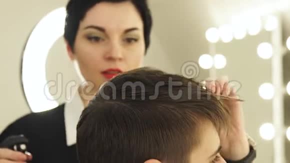 女理发师在美容院理发前用梳子梳理男头发并洒水发型师视频的预览图