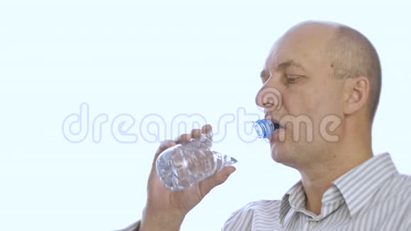 成年男子从白色背景的塑料瓶中饮水视频的预览图