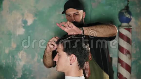 留胡子的理发师把发夹放在男人的头上然后刷他的头发理发店男性头上的发夹男性视频的预览图