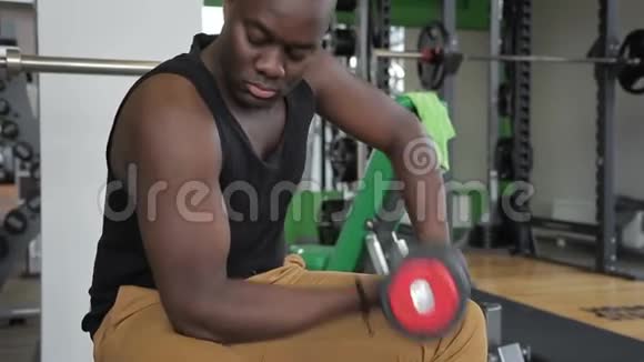 非裔美国人在健身房用哑铃摆动二头肌视频的预览图
