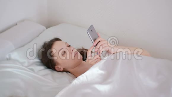 女人早上躺在床上看手机里的东西视频的预览图