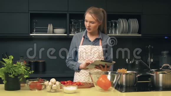 年轻女性做饭时使用平板电脑视频的预览图
