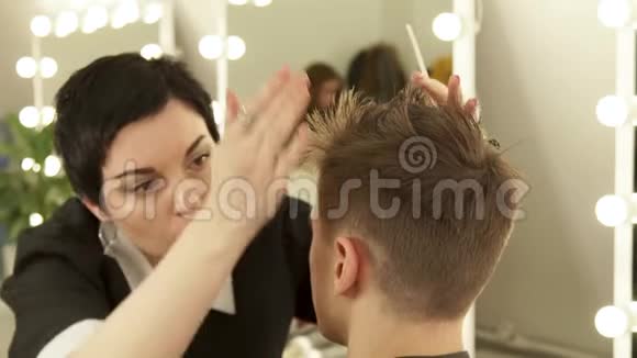 女理发师整理发型男式理发师在美发沙龙理发后梳理男性头发妇女视频的预览图