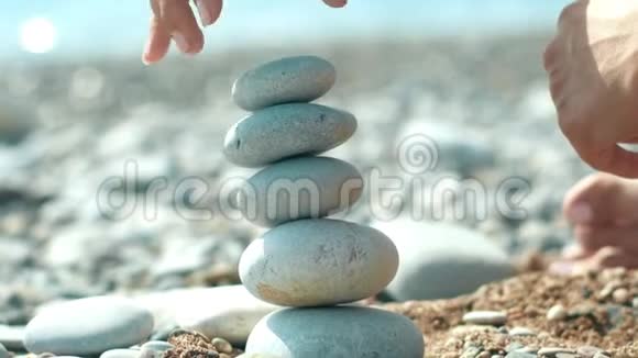 女人在假期在海滩上建造鹅卵石塔在海边放松视频的预览图
