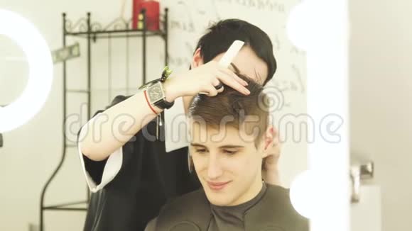 专业发型师在理发店理发女理发师用电动剃须刀剪雄头发视频的预览图