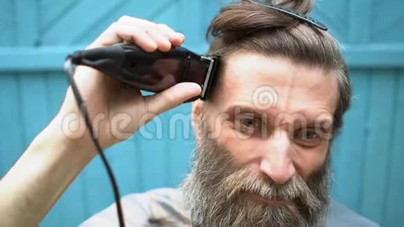 有胡子的奇怪男人试图用电动剃须刀剪自己的头发视频的预览图