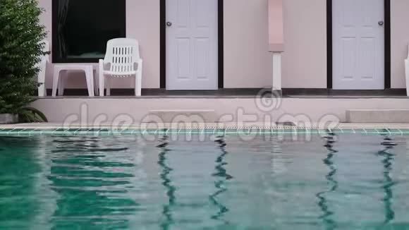 年轻女子在酒店游泳池放松和慢慢游泳暑假概念视频的预览图
