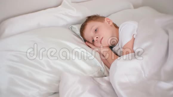 七岁的男孩静静地躺在他的房间里的床上双手放在他的头下视频的预览图
