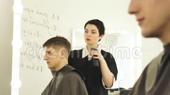 理发师在理发前喷洒水和梳理湿头发理发店的男性发型女理发师视频的预览图