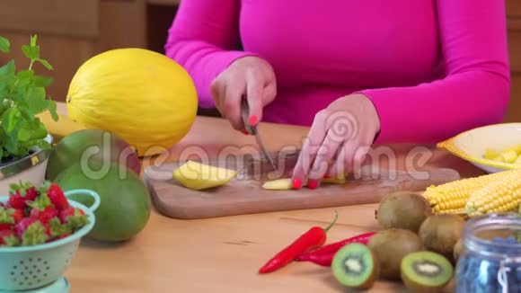 一个穿着粉色上衣的女人砍了一根辣黄芒果视频的预览图