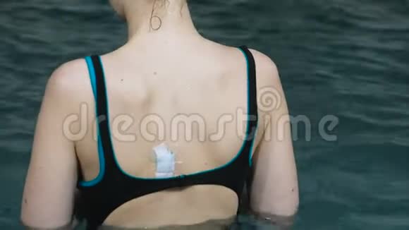 女人背上的防水补丁无法辨认的女人在游泳池里游泳视频的预览图