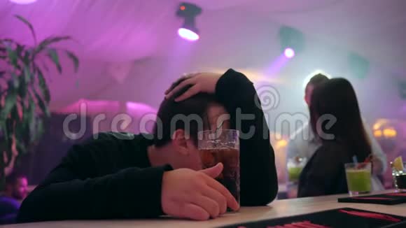 醉醺醺的孤独的家伙在酒吧柜台后面的灯光下喝着冰镇酒精视频的预览图