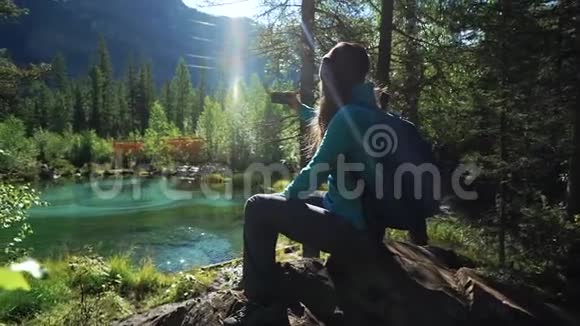 年轻的女游客背着背包坐在石头上正在欣赏美丽的蒙丹湖的风景视频的预览图