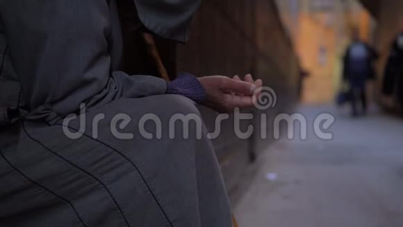 在杰拉巴拿着棍子的可怜的老人伸着手在费斯清真寺附近的街道上求饶视频的预览图