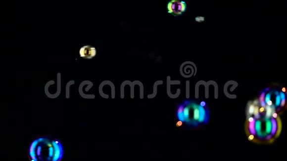 不同大小和颜色的肥皂泡飞得很近慢动作黑人背景视频的预览图