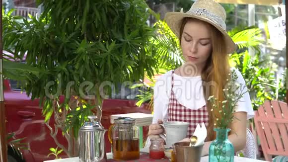 喝茶的女人茶锅蜂蜜果酱蛋糕和桌子上的花视频的预览图