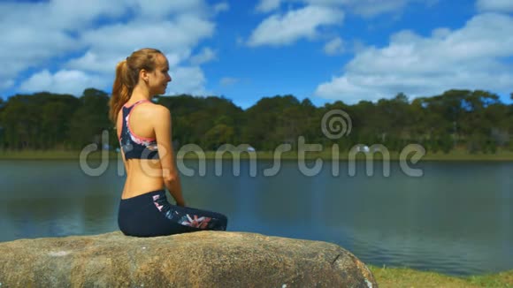 石头上的金发女郎看湖景视频的预览图