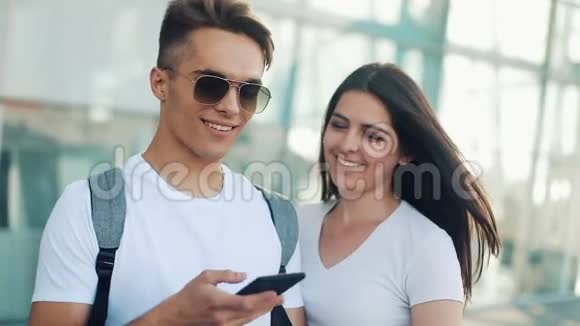 漂亮的年轻夫妇站在机场附近人叫出租车或叫快递服务通信视频的预览图