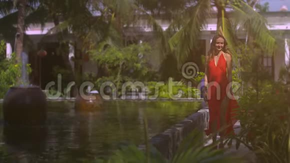 微笑的女人在热带花园的喷泉附近漫步视频的预览图