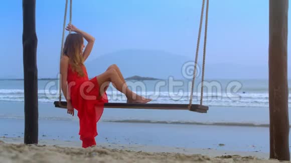 沙滩绳凳上的女孩游泳望蓝海视频的预览图