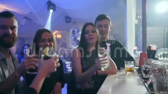 在夜总会酒吧柜台附近男人和年轻女人用五颜六色的鸡尾酒举杯祝酒玩得开心视频的预览图