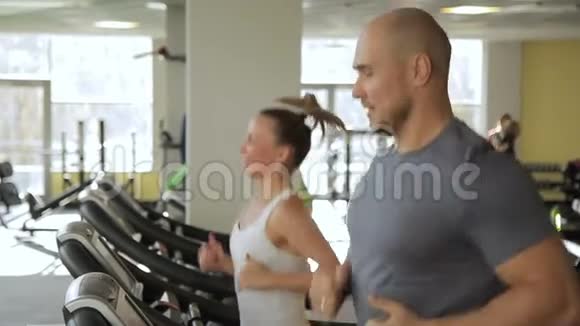 男人和女人在体育俱乐部的跑步机上跑步年轻夫妇慢跑视频的预览图