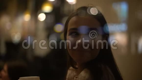 快乐的年轻女性在咖啡馆里喝咖啡看着窗户微笑着视频的预览图