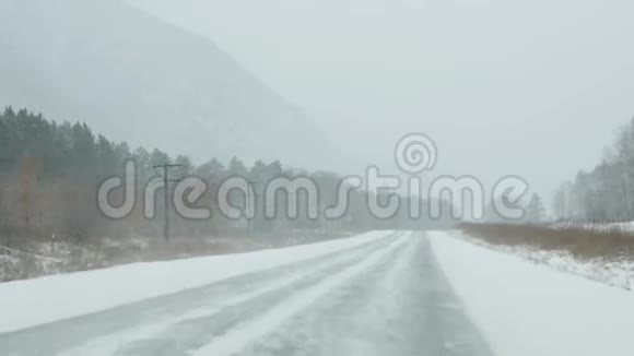 汽车在暴风雪中穿过森林透过挡风玻璃观看4K视频的预览图