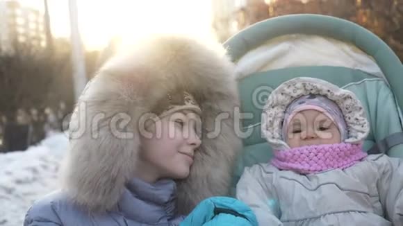 可爱的一岁女孩在婴儿车与姐姐散步在冬天视频的预览图