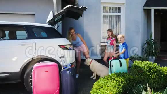 女人和她的孩子正在叫他们的狗上车然后把行李装上车视频的预览图