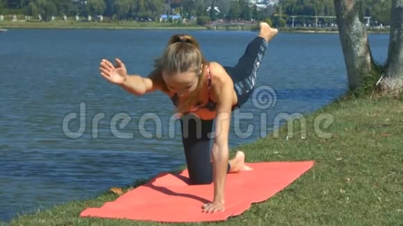 女孩站在湖岸草硬瑜伽位置视频的预览图