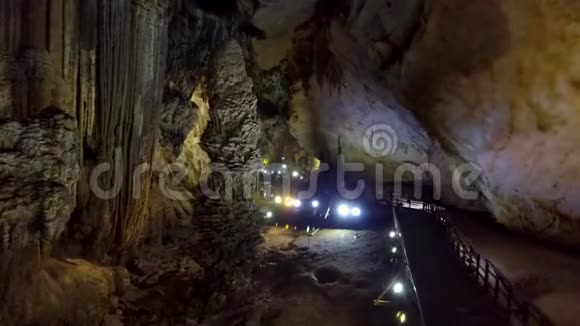 在巨大的喀斯特洞穴中通过桥梁接近彩色灯具的运动视频的预览图