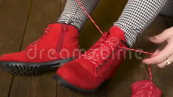 漂亮的女人穿着红色的鞋子在深色的木制背景上系鞋带视频的预览图