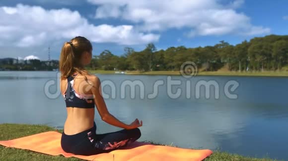 瑜伽姿势中的女孩手表湖和云反映视频的预览图
