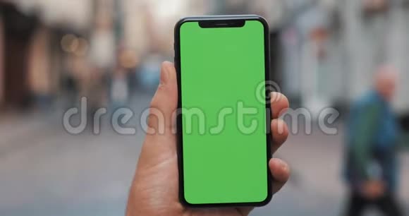 男性手拿黑色智能手机绿色屏幕在城市街道背景大屏幕铬钥匙快关门视频的预览图