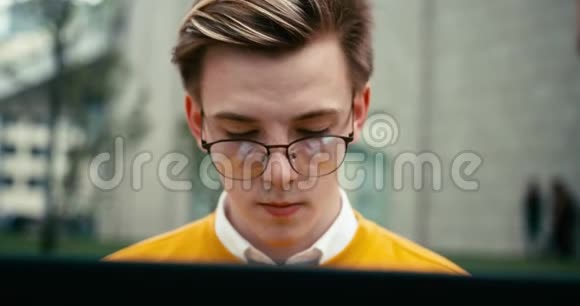 戴眼镜的沮丧青年在户外笔记本电脑上工作的肖像4K录像视频的预览图