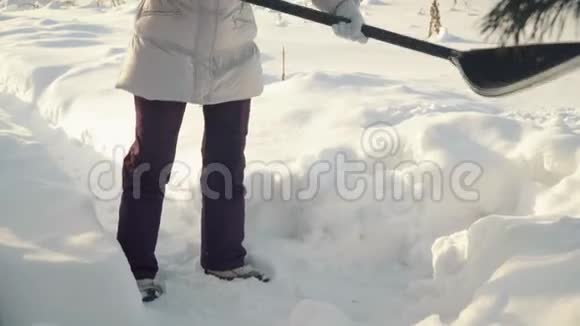年轻女子在冬天用铲子铲雪视频的预览图