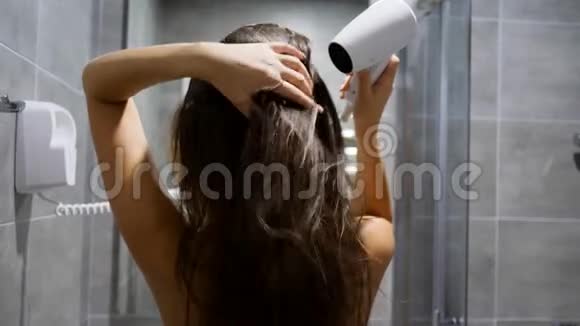 手拿电吹风在酒店客房浴室吹湿头发视频的预览图