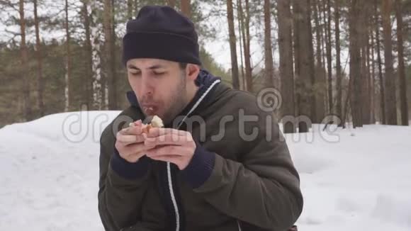 午餐在冬林一个男人在树枝上吃香肠视频的预览图