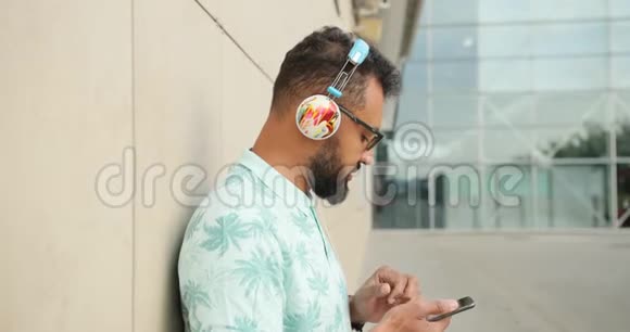 戴墨镜戴耳机欣赏音乐在手机上聊天的年轻非洲男子的侧面画像视频的预览图