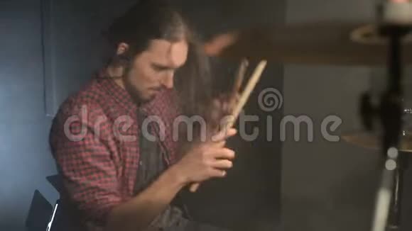 一位长头发的鼓手坐在鼓旁手里拿着鼓棒随着音乐的节拍在介绍中摇摆视频的预览图